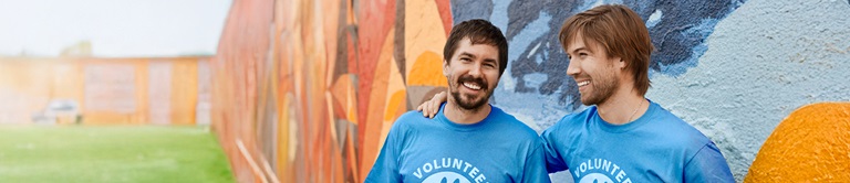 Two men smiling in blue volunteer t-shirts