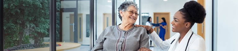 A women provider kneeling down next to senior citizen in wheelchair