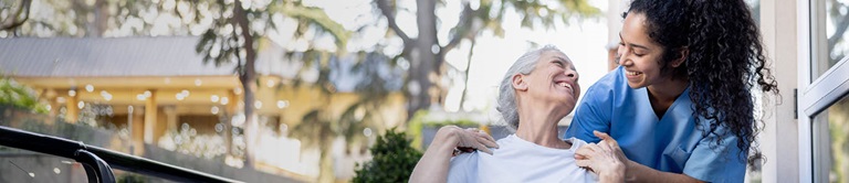 A provider with senior citizen patient smiling outside