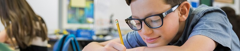 Boy writing at his school desk