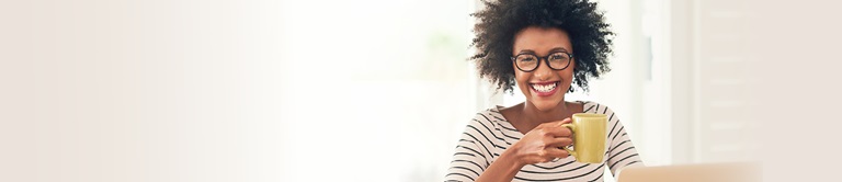 Woman holding a cup of coffee in front of a computer