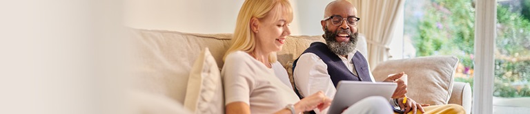 Two people looking at a tablet on the couch