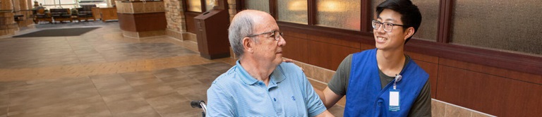 Young male volunteer assisting an elderly man in a wheelchair