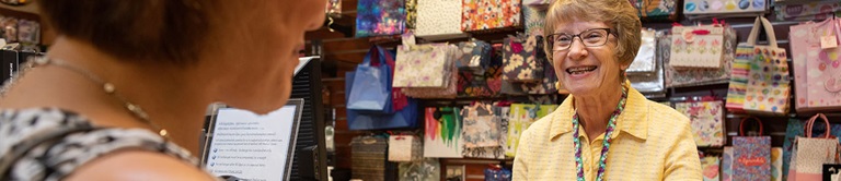 Retired female volunteer managing the gift shop check out counter