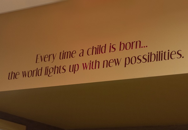 sign says every time a child is born the world lights up with new possibilities