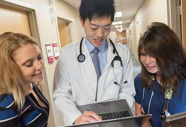 Resident and staff reviewing tablet in hallway