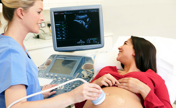 Radiology Tech looks at ultrasound with woman