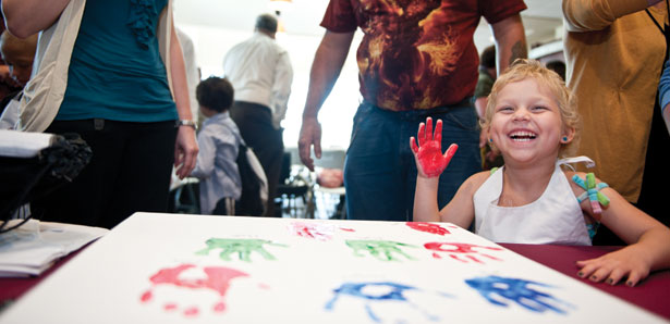 Young cancare patient leasves her hand print on a canvas commemorating a donation