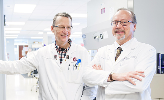 Medical researchers standing by equipment.