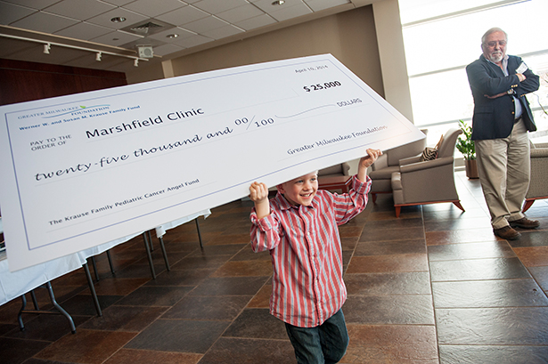 Will Krause, 5, runs with a check during a presentation in Marshfield Clinic's Erdman Lobby