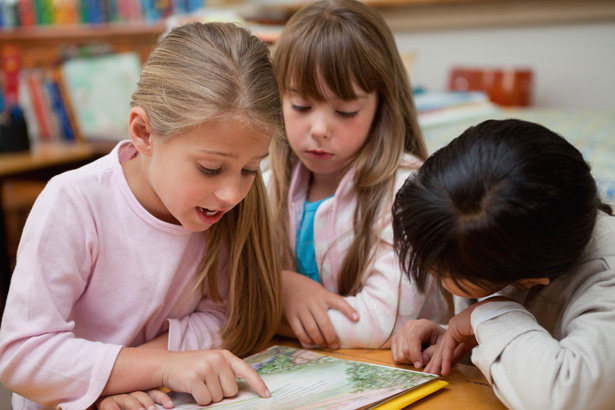 kids looking at a book together in school