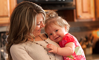 mom holding baby girl smiling