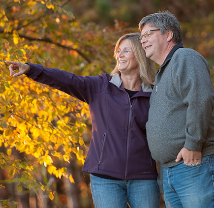 man and woman walk through woods